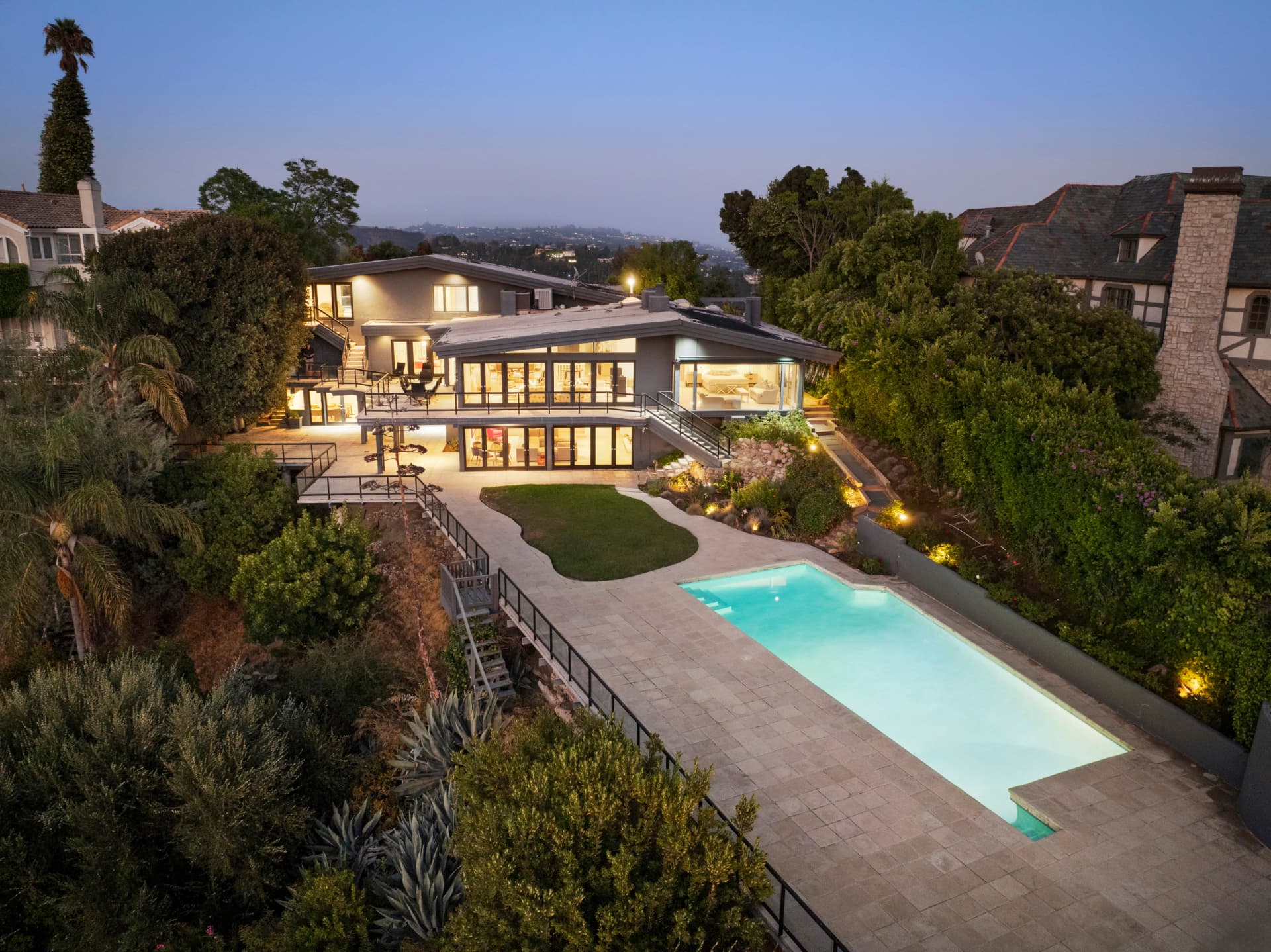 Terraced hillside pool and decks of a mid-century home in Bel Air at dusk