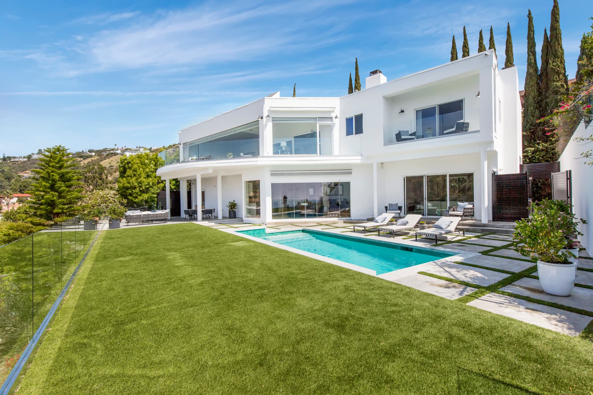 Lap pool and lawn beside a white two-story modern home in Santa Monica